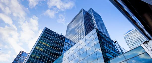 Modern glass skyscrapers in a financial district under a bright blue sky