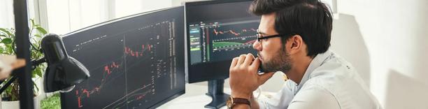 Businessman analysing data on multiple monitors, symbolizing financial markets and trading analysis