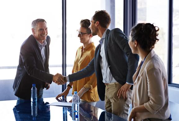 Business professionals shaking hands and smiling during a successful meeting in a modern office
