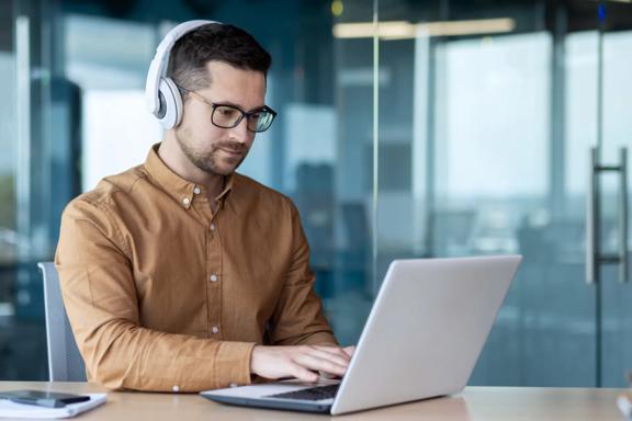 Investor working on a laptop while wearing headphones
