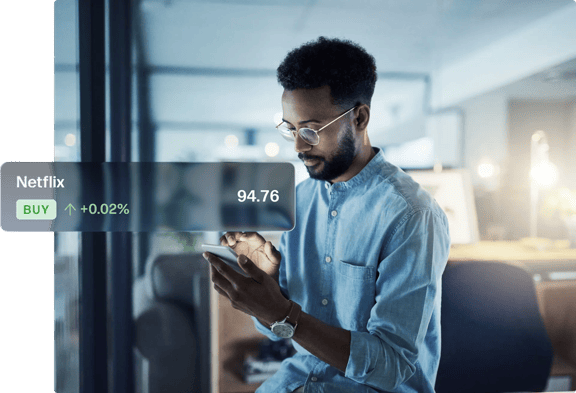 Person holding a smartphone in an indoor workspace with a digital stock price overlay showing a buy signal.