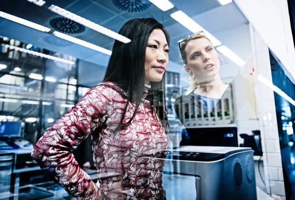 Two professional women analyzing data on a computer screen in a modern tech office.