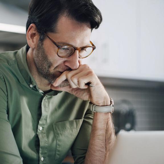 Professional with glasses and watch and analyzing data in laptop.