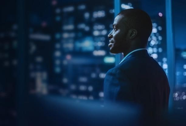 Professional man looking out office window at night