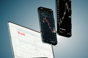 Trading platform in light theme on a laptop and on two smartphones in dark mode