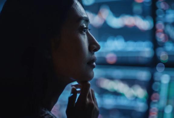 Woman gazing at blurry screens showing financial data