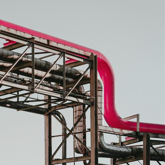Industrial metal pipelines and steel framework at a processing facility.