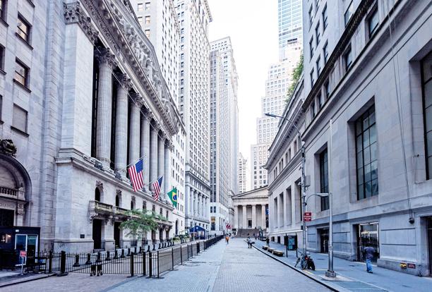 Vista da Wall Street em Nova York com prédios financeiros históricos e bandeiras americanas