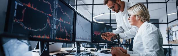 Traders working with multiple monitors to manage FX and interest rate risk in financial markets