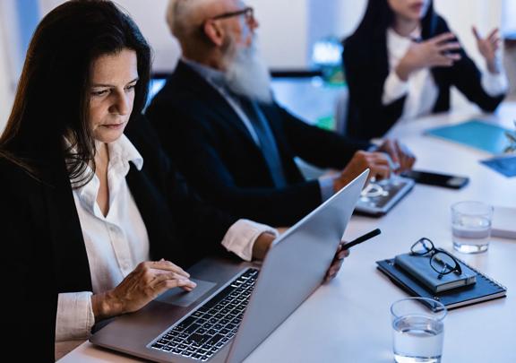 Focused Businesswoman Using Laptop During Strategy Meeting