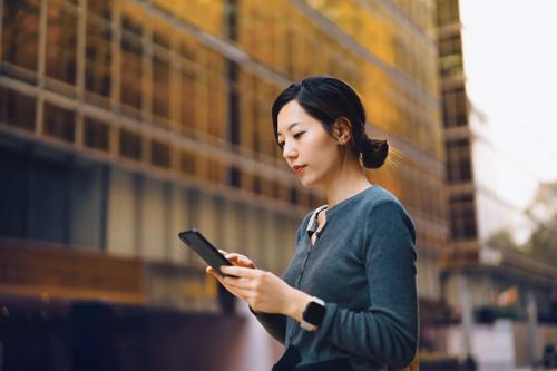 Woman holding smartphone outside office building
