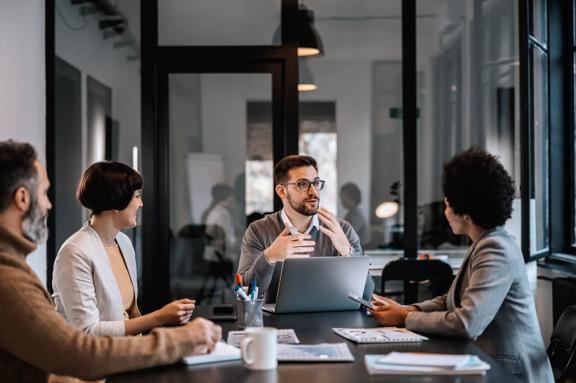 Um mentor focado está explicando o projeto aos mentorandos na sala de reuniões da empresa em um escritório moderno