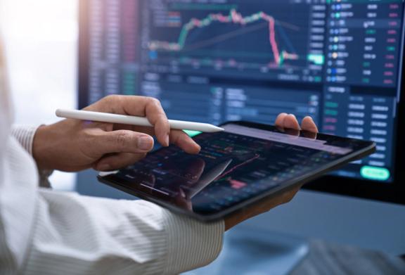 Close-up de uma pessoa usando um tablet com uma caneta stylus para analisar dados financeiros em uma plataforma de negociação