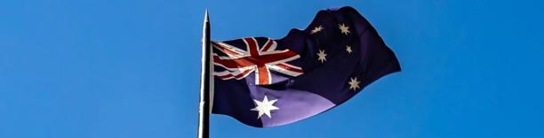 Australian national flag waving proudly in the wind under a clear blue sky, symbolizing the country's economy and trade outlook