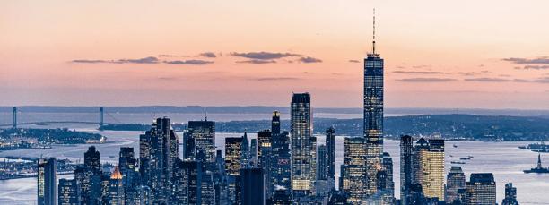 Panoramic view of the New York City skyline at sunset featuring One World Trade Center