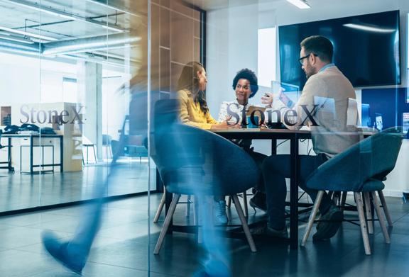 Profissionais de negócios em uma sala de reuniões da StoneX colaborando por meio de discussões e dispositivos digitais