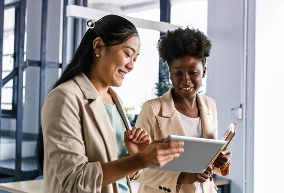 Two professionals collaborating on a tablet in a modern office setting.