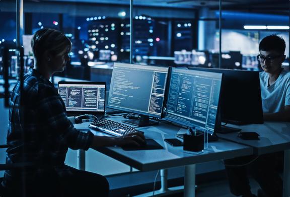 Two professionals sitting opposite each other working on their computers in an office at night