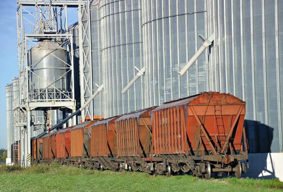 Vagões de trem de carga carregados com carga perto de silos industriais em uma instalação de armazenamento de grãos.