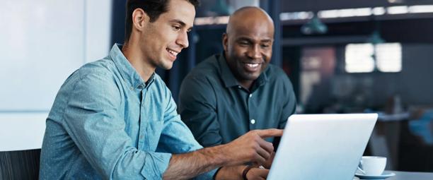 Two traders analyzing market data on a laptop screen in an office