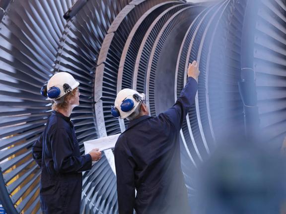 Engineers inspecting large turbine components inside an industrial facility