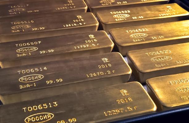 Stacked gold bars stamped with purity and origin markings, representing precious metals trading and wealth storage.

