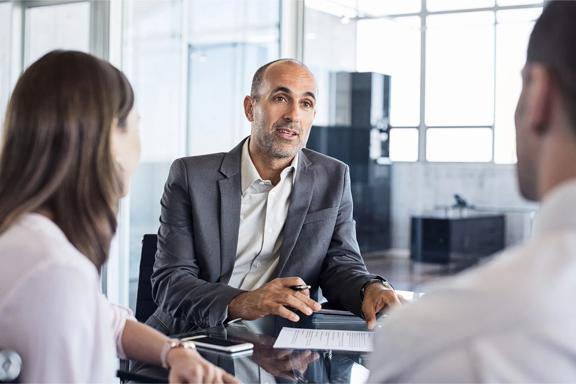 Three people are discussing a business meeting.