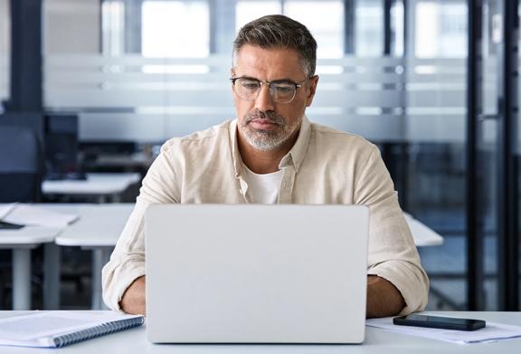 Man working on a laptop in a modern office environment.