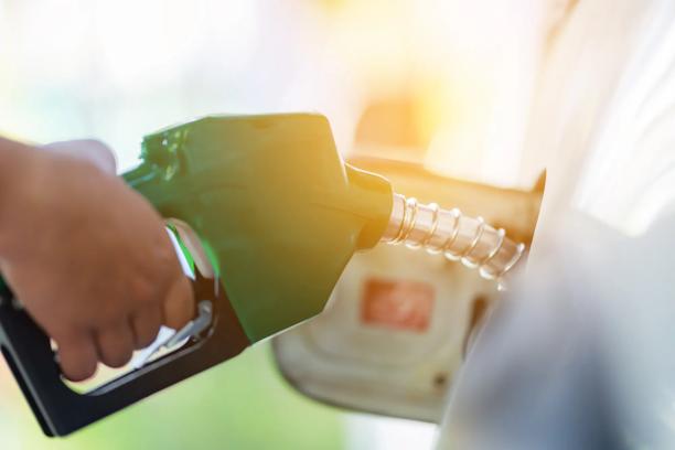 Homem manuseia o bico de combustível de gasolina para reabastecer.