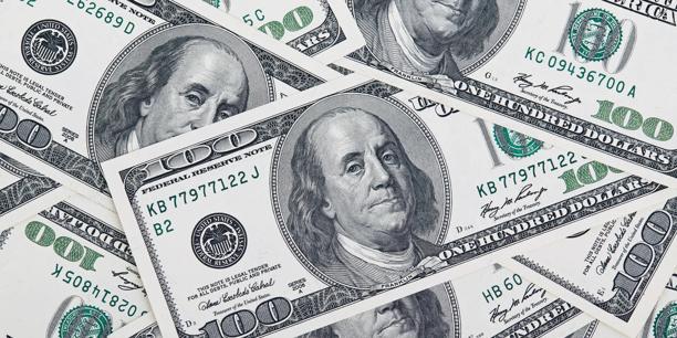 Close-up de várias cédulas de cem dólares americanos sobrepostas em uma disposição padronizada.