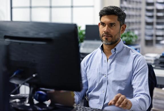 Business professional using a desktop computer in a modern office, representing hosted FX payments platform.