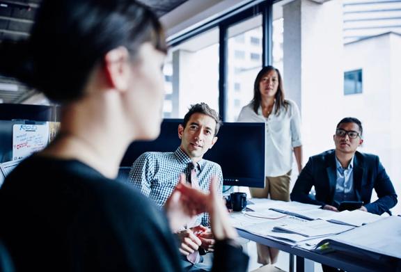 Focus on a woman presenting and colleagues listening attentively.
