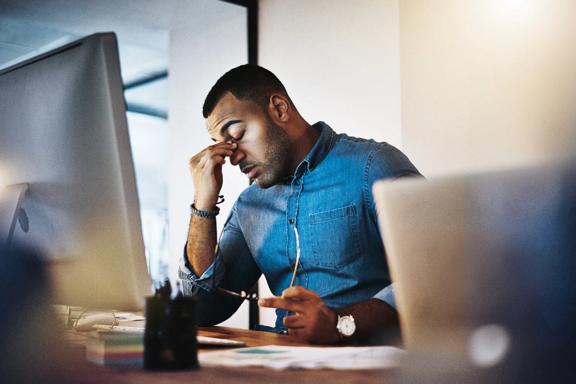 Business professional sitting at a desk with hand on forehead