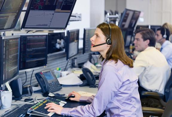 Profissional de negócios discutindo tendências de mercado ao telefone enquanto analisa gráficos financeiros em várias telas