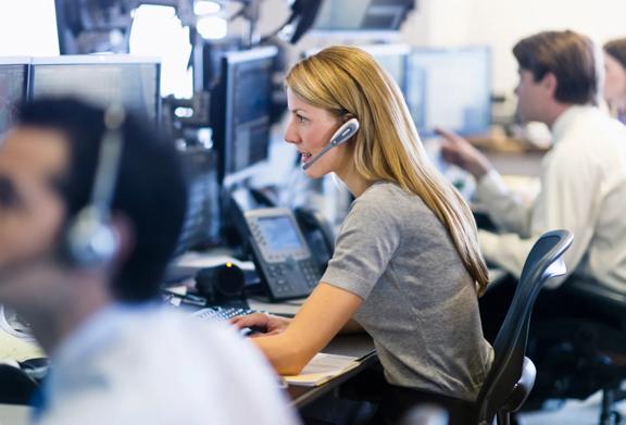 Focused call center operator wearing a headset and working at a computer in a busy office