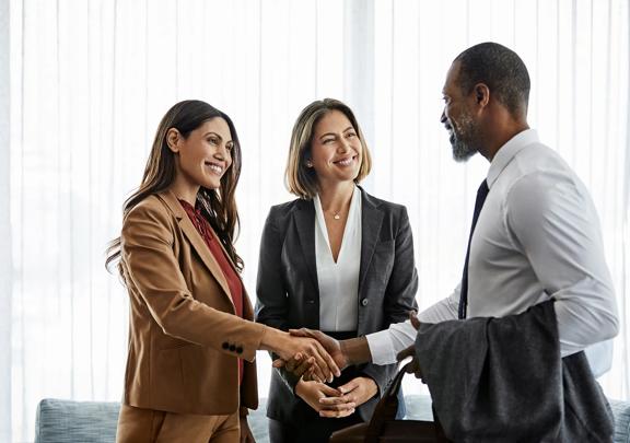 Two women and a man smiling and shaking hands