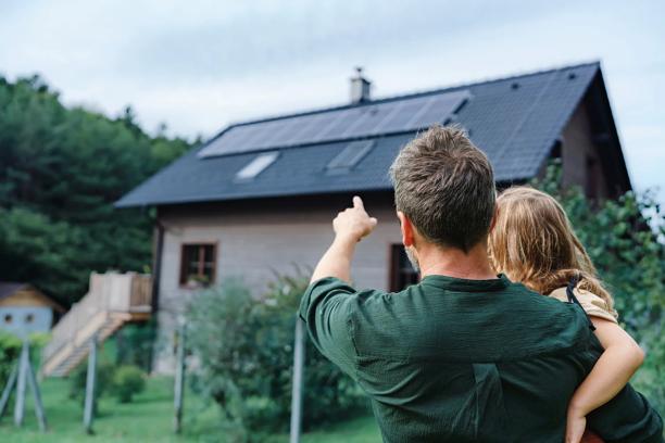 Pai e filho olhando para uma casa com painéis solares instalados no telhado