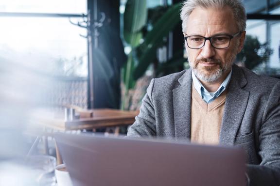 Experienced professional working on a laptop in a modern office environment.