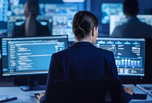 Woman looking at two screens showing financial data