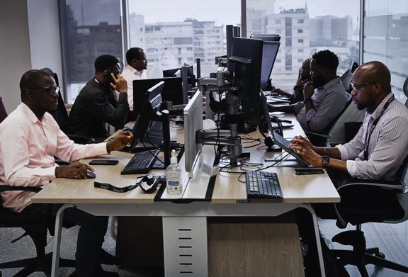StoneX employees working at their laptops in the Nigeria office