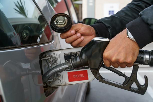 Pessoa abastecendo um veículo com diesel em posto de combustível, destacando o bico da bomba inserido no tanque.