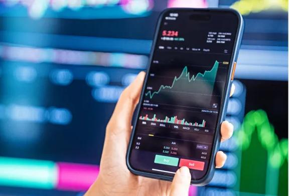 Mão segurando smartphone com aplicativo de trading exibindo gráfico do mercado e opções de compra e venda