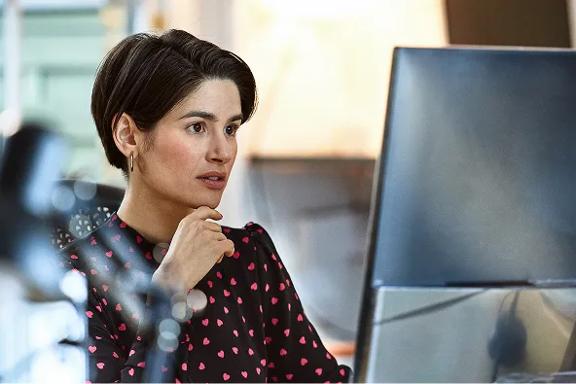 Profissional analisando informações em monitor de computador, ambiente de trabalho moderno