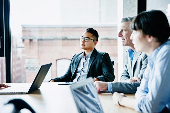 Executivos de negócios discutindo estratégias em torno da mesa em escritório com vista para a cidade