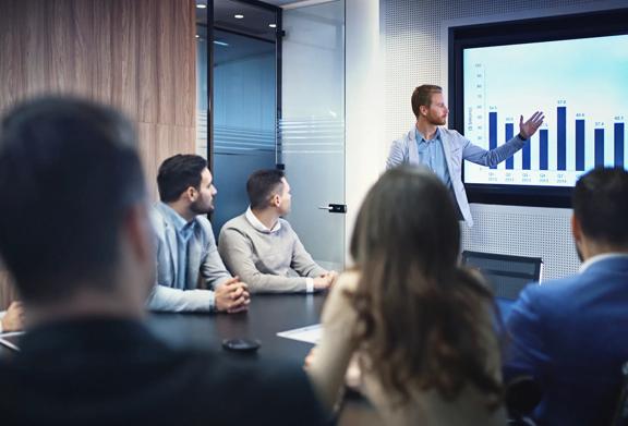 Business professional presenting data on a screen during a corporate meeting