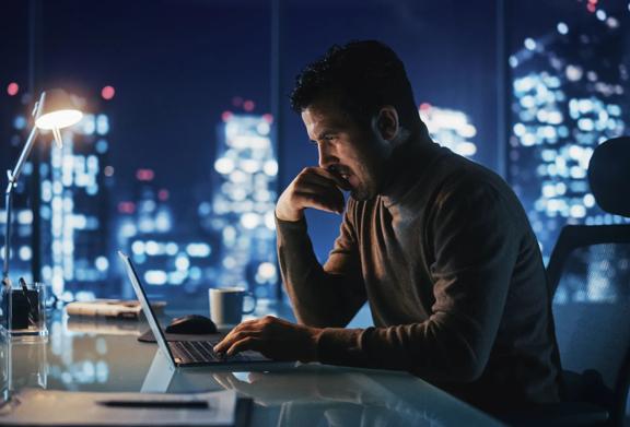 Professional analyzing data and making market decisions after hours in a modern financial office
