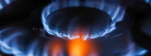 Close-up of a lit natural gas burner with blue flame, representing energy usage and fuel efficiency.