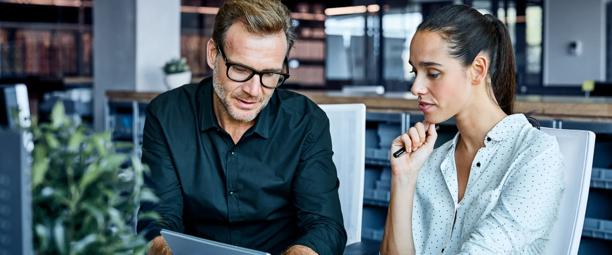Business colleagues collaborating and discussing data on a tablet in a modern office setting