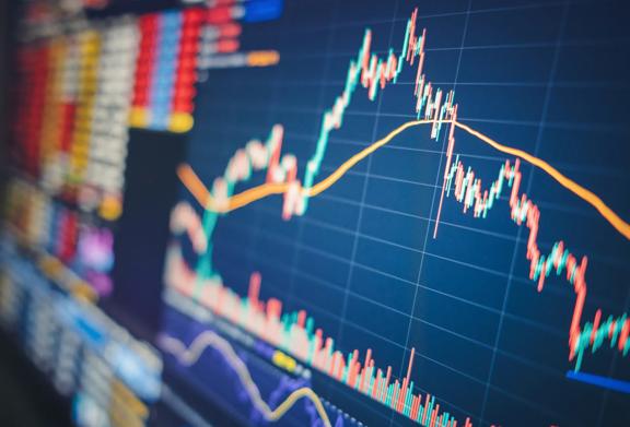 Close-up de um gráfico financeiro com dados do mercado de ações, incluindo padrões de velas e médias móveis