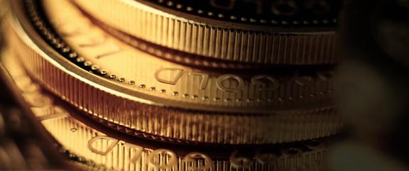Macro view of stacked gold coins showing detailed ridged edges and engraved text
